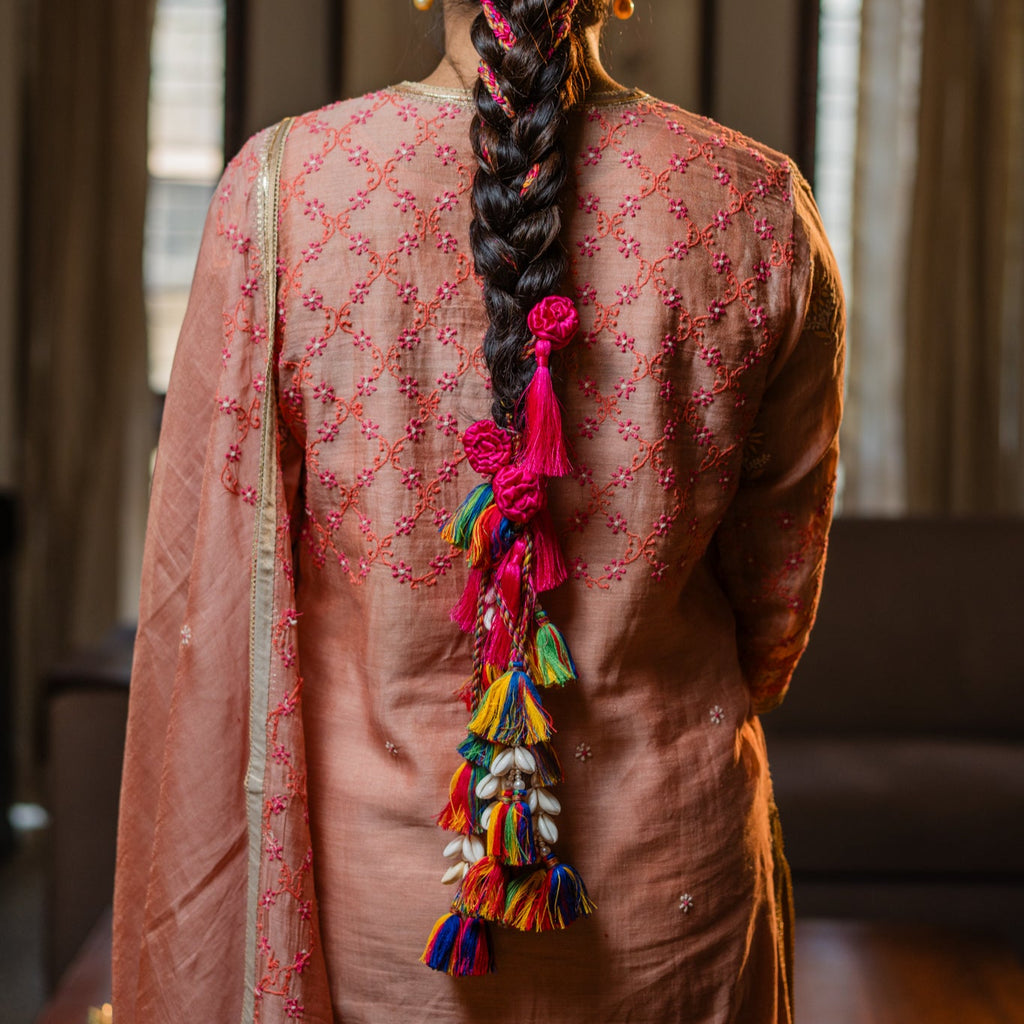 Person wearing a traditional outfit with a colorful braid in an indoor setting